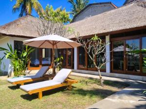 2 tumbonas y una sombrilla frente a una casa en Guava Garden, en Gili Trawangan