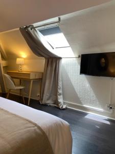 a room with a bed and a window and a desk at Hotel l'Avenue in Chantilly