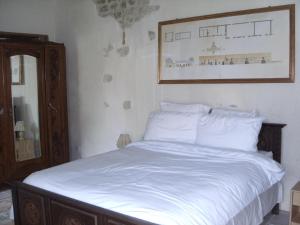 a bed with white sheets and a picture on the wall at Gîte de l'Octroy Poitou in Oiron