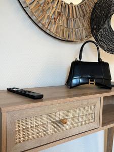 eine schwarze Handtasche auf einer hölzernen Kommode in der Unterkunft Hotel l'Avenue in Chantilly