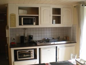 a kitchen with white cabinets and a microwave at L Ermitage ST Roch appartement ST André in Salins-les-Bains