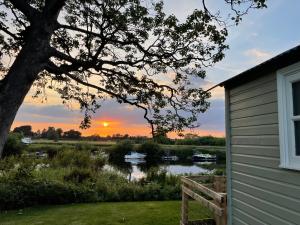 a sunset over a river next to a house at The Hut by the River in York