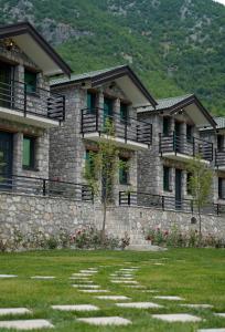 a stone building with a grass yard in front of it at Bujtina Adora 