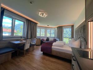 a hotel room with a bed and a desk and windows at Apart Lech in Holzgau