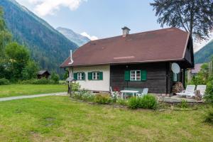 馬爾尼茨的住宿－Cottage Hohe Tauern，院子里的房屋,设有绿色百叶窗和椅子
