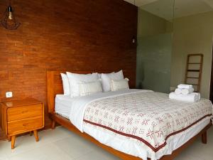 a bedroom with a bed and a brick wall at Villa Sandhyā Tabanan in Tabanan +18 photos