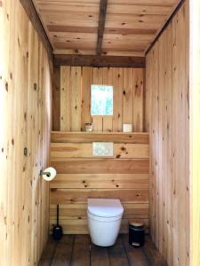 een badkamer met een toilet in een houten muur bij Cowcooning / Family tents in Huldenberg