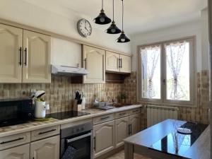 Saint-Christol-lès-AlèsにあるJolie maison à louer dans les Cévennesの白いキャビネットと壁掛け時計付きのキッチン