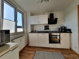 a kitchen with white cabinets and a large window at FEWODAYs Ferienwohnung in Sassnitz - Ruegen in Sassnitz