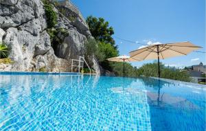a large swimming pool with an umbrella and a mountain at Beautiful Home In Kostanje With Wifi in Kostanje