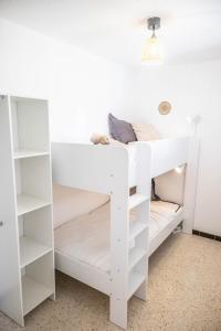 Cette chambre comprend un lit superposé blanc avec des étagères blanches. dans l'établissement LE WHITE - CLIM PARKING WIFI 5min PLAGE NEUF 6MAX -TOP PROS SERVICESConciergerie, à La Grande Motte