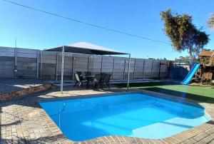 a swimming pool with a table and chairs in a yard at Arlogenix in Durbanville