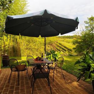 蒙泰羅尼達爾比亞的住宿－Agriturismo La Roverella，露台的遮阳伞下的桌椅