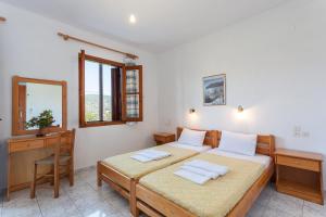 a bedroom with a bed and a desk and window at Platanakia in Skopelos Town