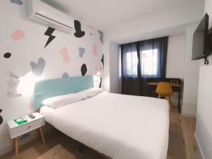 Un dormitorio con una cama blanca y una pared con corazones en Hostal Carmen by gaiarooms, en Salamanca