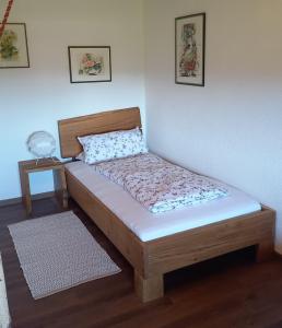 a wooden bed in a room with a white wall at Huis am Berg in Immenstadt im Allgäu