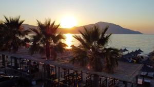 - une vue sur une plage bordée de palmiers et le coucher du soleil dans l'établissement Hotel Amantia, à Orikum