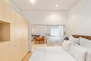 een witte slaapkamer met een bed en een eetkamer bij Glaston House Vibey City Centre Free Parking Aircon in Kaapstad
