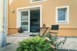 deux chaises et une table devant une maison dans l'établissement Apartment Haus Inge, à Dürrröhrsdorf