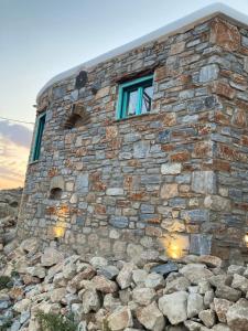 a stone building with a window on top of a pile of rocks at Dimitrakis Guesthouse in Donoussa