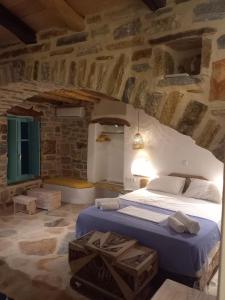 a bedroom with a large bed in a stone wall at Dimitrakis Guesthouse in Donoussa