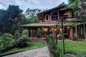 ein Haus mit einem roten Haus mit einer Veranda in der Unterkunft Casa Charmosa na Serra de Mulungu por Carpediem in Mulungu