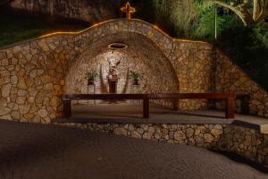 a church with a cross and a bench in a stone wall at Hotel Saint Michel in Monte Verde