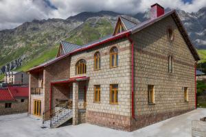 a large brick building with mountains in the background at GRAF Kazbegi in Stepantsminda