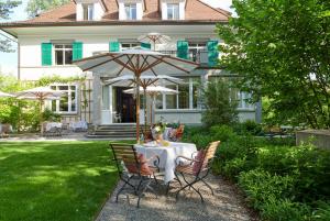 a table with an umbrella in front of a house at Signau House & Garden Boutique Hotel Zürich in Zürich