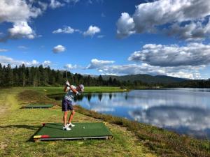 a man swinging a golf club at a lake at Hovdestøylen in Hovden
