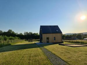 a small house in a field with the sun in the sky at Dom Wśród Gwiazd in Jarnołtówek