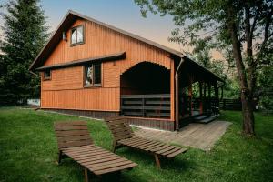 a barn with two benches in front of it at Domki nad potokiem in Susiec
