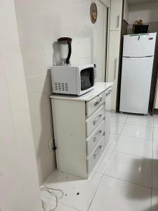 a kitchen with a microwave on a counter with a refrigerator at Apto Central para Família in Balneário Camboriú