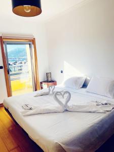 een bed met twee hartvormige handdoeken erop bij Cabedelo guest house in Viana do Castelo