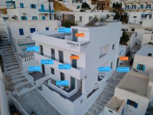 Vista árida de un edificio blanco con signos azules y naranjas en Bedspot Apartments Astipalaia en Pera Gyalos