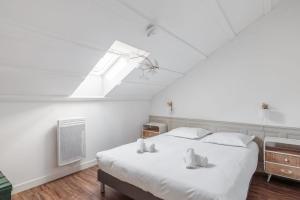 1 dormitorio con 1 cama blanca grande y tragaluz en Maison Ferry - Welkeys, en Rivedoux-Plage