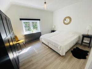 a white bedroom with a bed and a window at Lovely, renovated appartment, near the beach. in De Haan