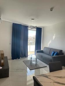 uma sala de estar com um sofá azul e uma mesa em Blu-M Central em Qormi