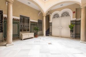 un hall avec des colonnes et un escalier dans un bâtiment dans l'établissement Apartamentos Plaza Nueva, à Séville