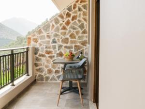 a table on a balcony with a stone wall at Sisaion Suites - Live the Cretan Hospitality in Metókhion Apisianá