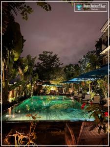 uma grande piscina à noite com luzes acesas em Blooms Boutique Village em Hoi An