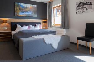 a bedroom with a bed and a chair and a window at Berghotel TheLounge in Berwang