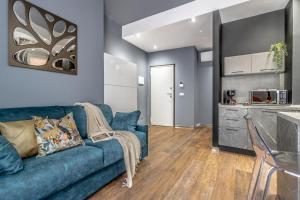 uma sala de estar com um sofá azul e uma cozinha em Ugo Bassi Apartments em Bolonha