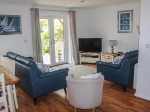 Sala de estar con 2 sillas azules y TV en Robinswood, en Falmouth