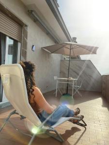 une femme assise sur une chaise sous un parapluie dans l'établissement Attico Guest House, à Crémone
