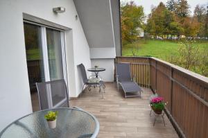 eine Terrasse mit einem Glastisch und Stühlen auf dem Balkon in der Unterkunft Apartments Fine Stay Slovenia in Žirovnica