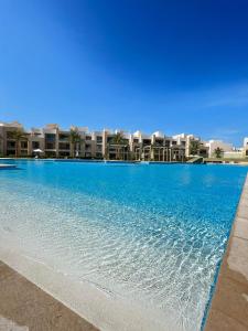 a large swimming pool with buildings in the background at Taj Home, Mangroovy, pool view, free beach access with nanny's room in Hurghada