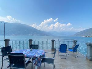 a table and chairs on a balcony with a view of the water at Apartment with Big Terrace and Direct access to the Beach in Varenna