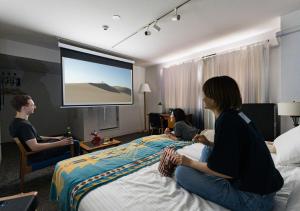 a group of people sitting on beds in a hotel room at Hotel Graphy Nezu in Tokyo