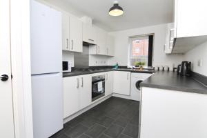 a kitchen with white cabinets and black counter tops at 7Bed City Gem - Walk to Coventry Center, Ultimate Holiday Comfort in Coventry